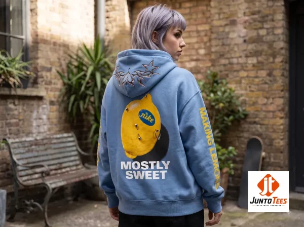 Back view of a blue hoodie featuring a printed lemon graphic with silver rings and the text MOSTLY SWEET.