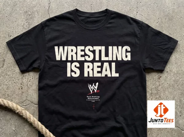Rey Mysterio Travis Scott WWE Wrestling Is Real T-Shirt 1 A wrestling fan wearing the black Wrestling Is Real t-shirt in a dimly lit backstage atmosphere.