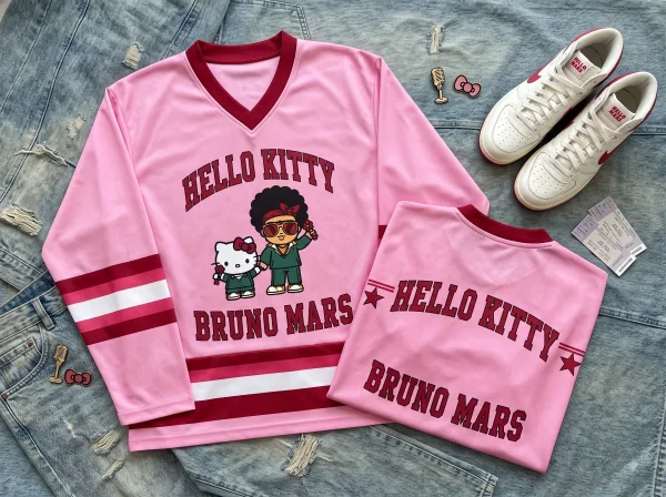 Front view of Hello Kitty and Bruno Mars pink varsity jersey with red graphic typography on denim background